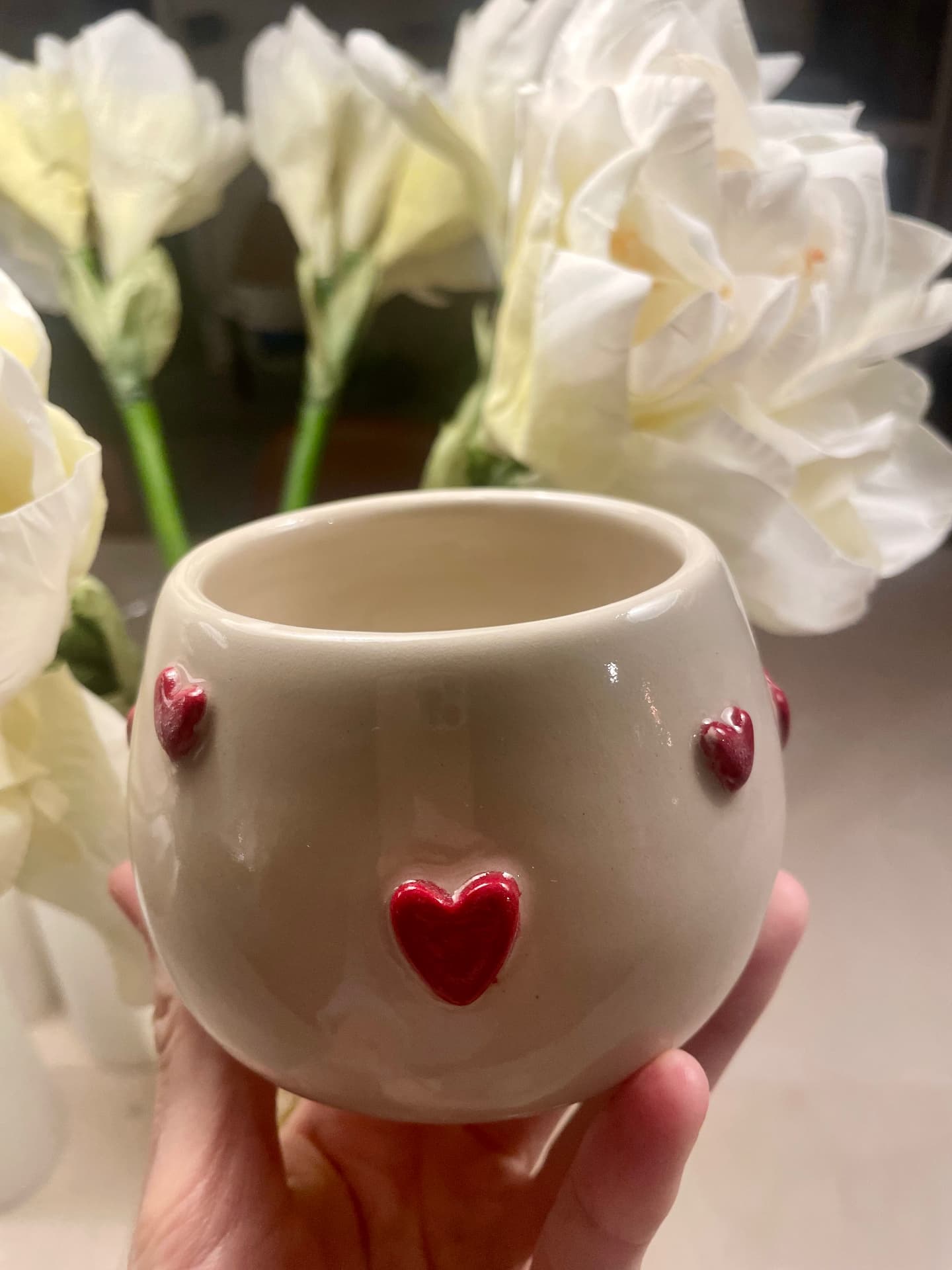 Close-up of cream cup with hand-built red hearts